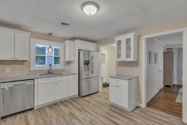 kitchen featuring visible vents, light wood-type flooring, a sink, appliances with stainless steel finishes, and white cabinets