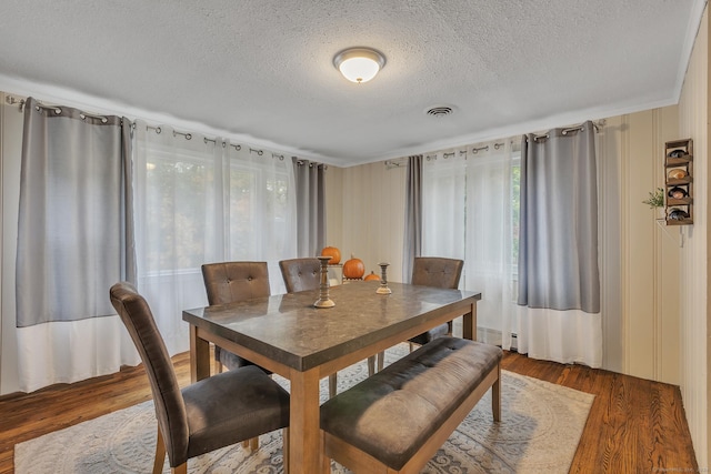 dining room with visible vents, a textured ceiling, and wood finished floors