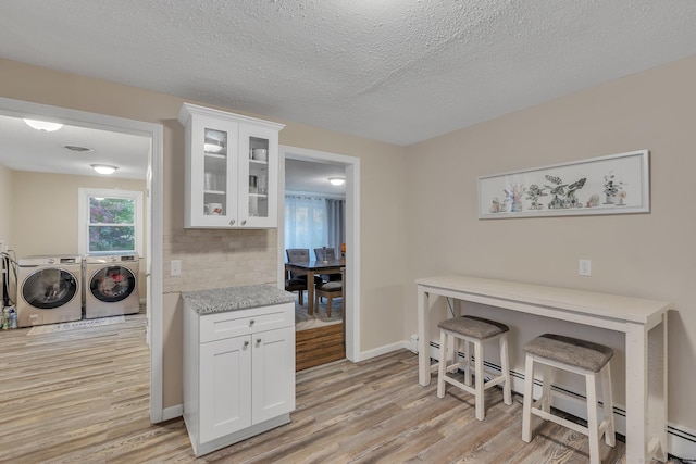 kitchen with glass insert cabinets, white cabinetry, light wood-style flooring, and washer and clothes dryer