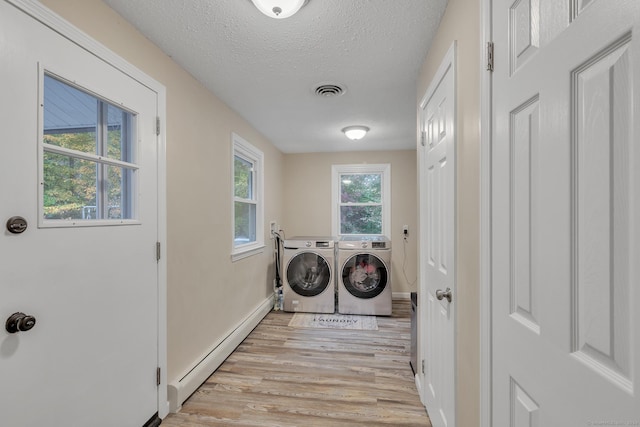 washroom with laundry area, light wood-style floors, washer and dryer, a textured ceiling, and a baseboard radiator