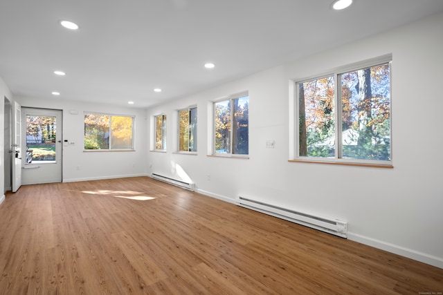 interior space with a healthy amount of sunlight, a baseboard radiator, and hardwood / wood-style floors