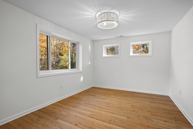 spare room featuring light hardwood / wood-style floors and an inviting chandelier