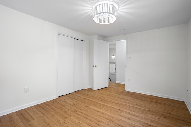 unfurnished bedroom with a closet, a chandelier, and light wood-type flooring