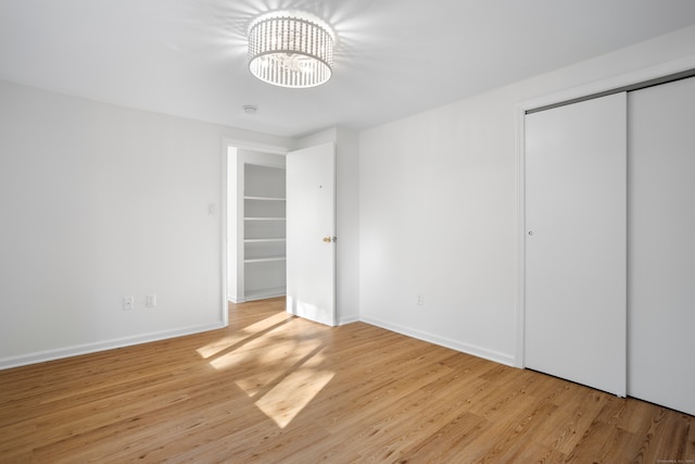 unfurnished bedroom with a closet, a notable chandelier, and light hardwood / wood-style floors