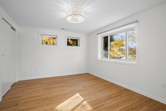 empty room featuring a notable chandelier and light wood-type flooring