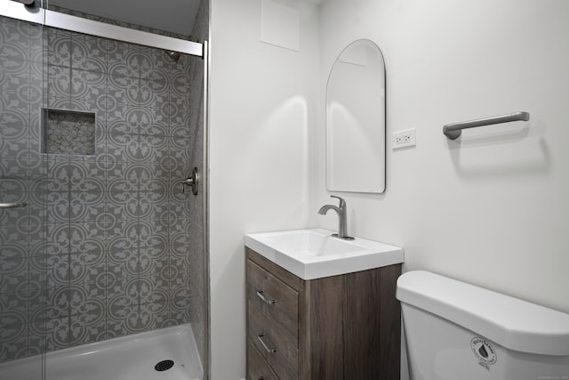 bathroom featuring vanity, toilet, and tiled shower