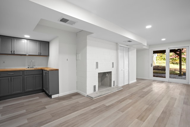 unfurnished living room featuring a large fireplace, wet bar, and light hardwood / wood-style flooring