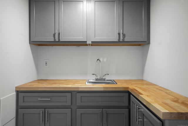 bar with gray cabinetry, wood counters, and sink