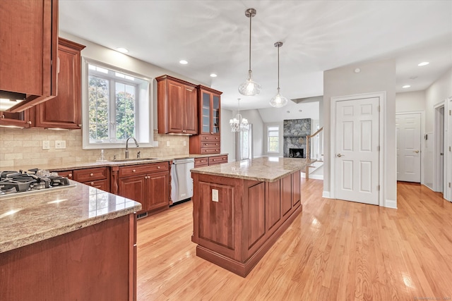 kitchen featuring appliances with stainless steel finishes, light wood-type flooring, sink, a fireplace, and a center island