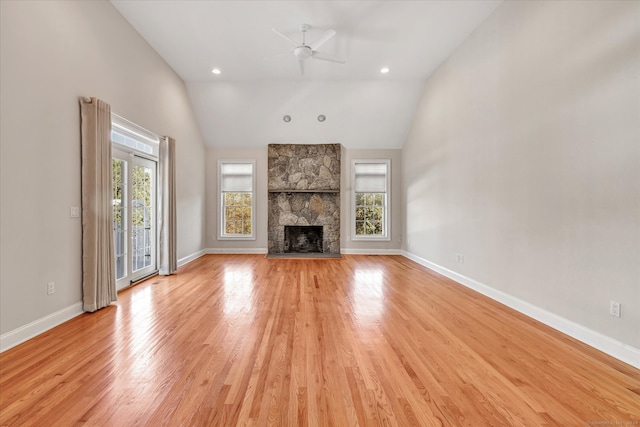 unfurnished living room with a stone fireplace, a wealth of natural light, and light wood-type flooring