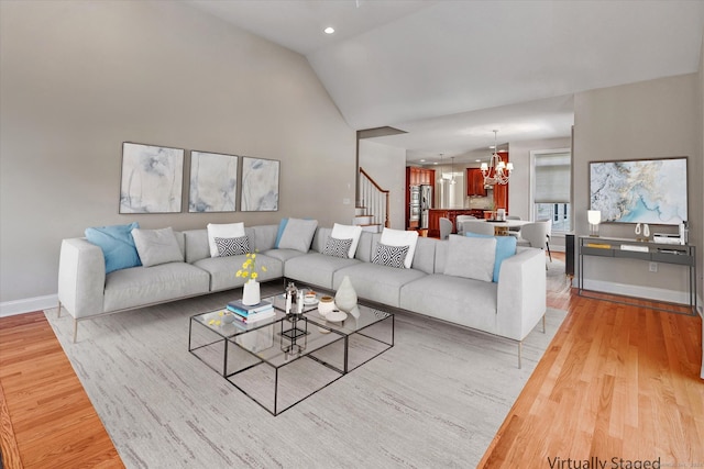 living room featuring an inviting chandelier, hardwood / wood-style flooring, and vaulted ceiling