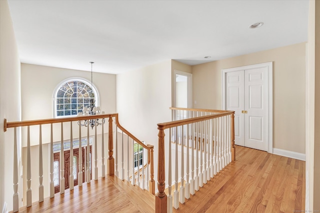 hallway with light hardwood / wood-style flooring and a chandelier