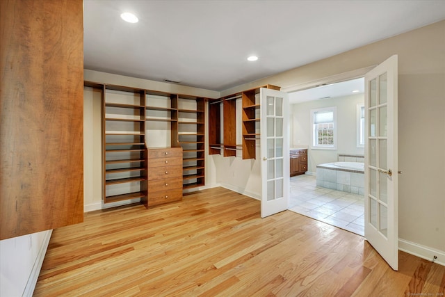 walk in closet featuring french doors and light hardwood / wood-style floors