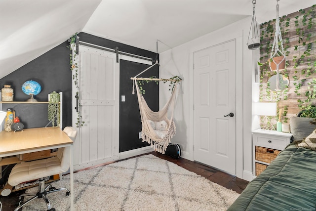 interior space with vaulted ceiling, a barn door, and dark hardwood / wood-style flooring