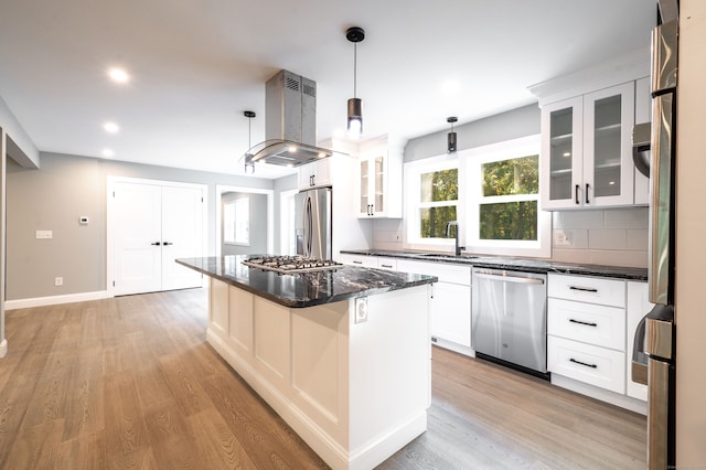 kitchen with appliances with stainless steel finishes, island range hood, a center island, hanging light fixtures, and white cabinets