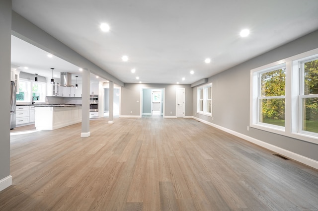 unfurnished living room featuring light wood-type flooring and a wealth of natural light