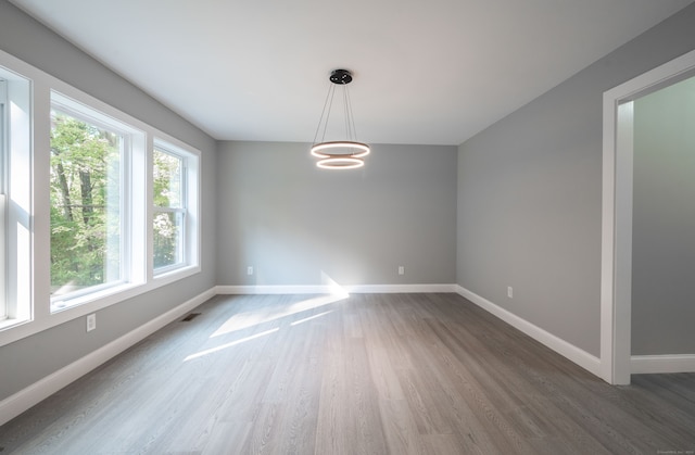 unfurnished dining area featuring a notable chandelier and dark hardwood / wood-style flooring