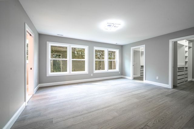 unfurnished bedroom with a closet, hardwood / wood-style floors, and a spacious closet