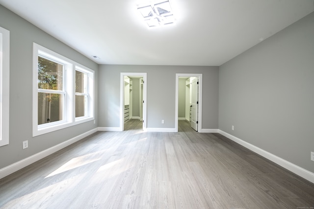 unfurnished bedroom with light hardwood / wood-style flooring, a walk in closet, a closet, and connected bathroom