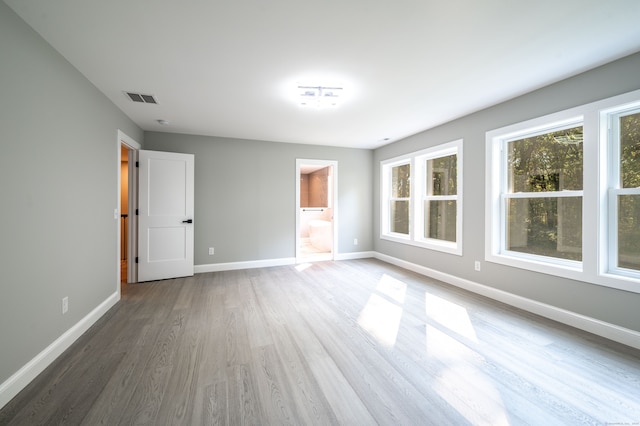 unfurnished bedroom featuring ensuite bathroom and hardwood / wood-style flooring