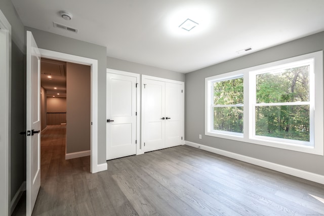 unfurnished bedroom featuring multiple closets and wood-type flooring