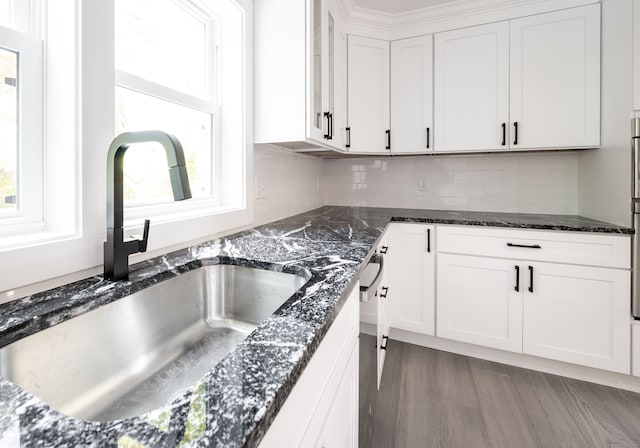 kitchen with backsplash, dark stone countertops, sink, light wood-type flooring, and white cabinetry