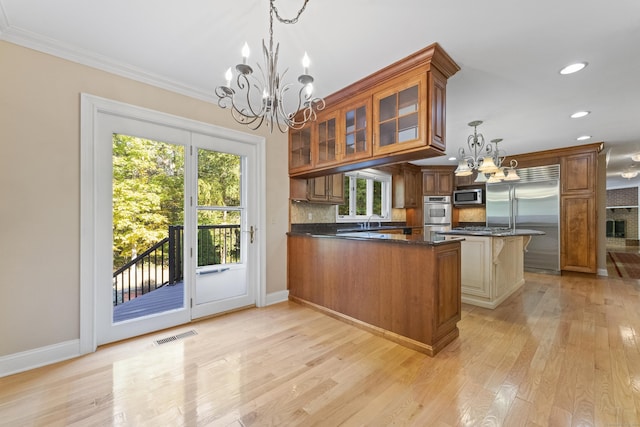 kitchen with decorative light fixtures, light wood-type flooring, stainless steel appliances, and a chandelier