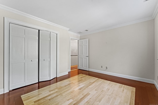 unfurnished bedroom featuring crown molding, a closet, and dark hardwood / wood-style floors