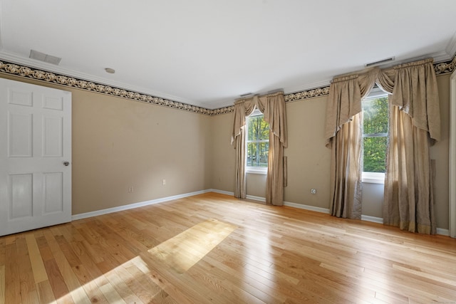 unfurnished room featuring light wood-type flooring, plenty of natural light, and ornamental molding