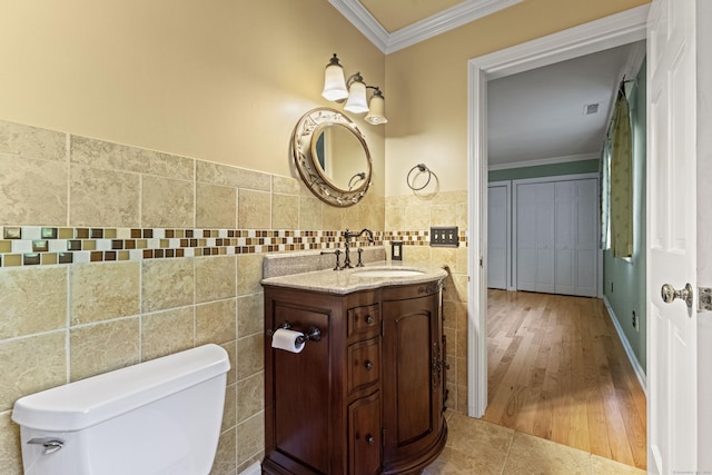 bathroom with vanity, tile patterned floors, crown molding, toilet, and tile walls