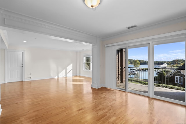 empty room featuring crown molding, a water view, and light hardwood / wood-style floors