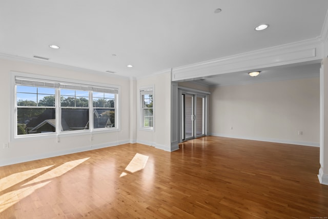 unfurnished room with a wealth of natural light, crown molding, and wood-type flooring