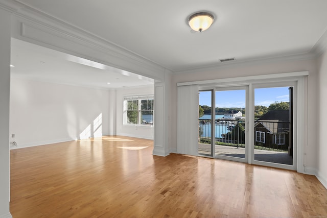 empty room with a water view, crown molding, and light hardwood / wood-style flooring