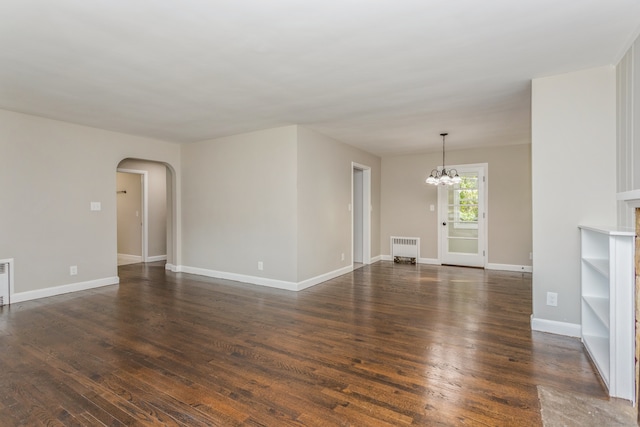 unfurnished living room featuring an inviting chandelier, dark hardwood / wood-style flooring, and radiator