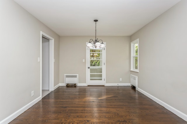 unfurnished dining area featuring a notable chandelier, dark wood-type flooring, and radiator heating unit