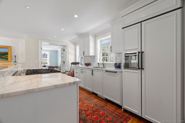 kitchen with ornamental molding, a sink, tasteful backsplash, white cabinetry, and dishwasher