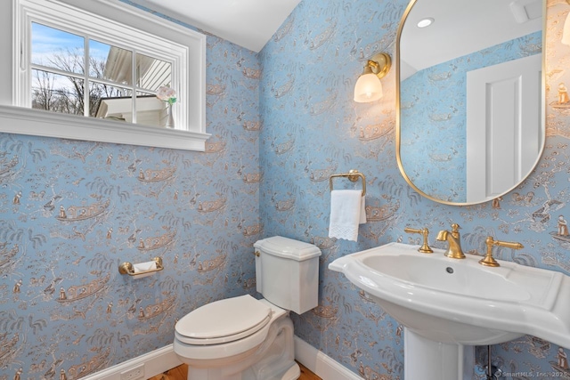 bathroom with wallpapered walls, toilet, baseboards, and a sink