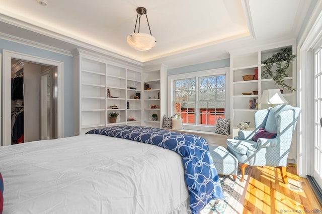 bedroom featuring ornamental molding, a tray ceiling, and wood finished floors