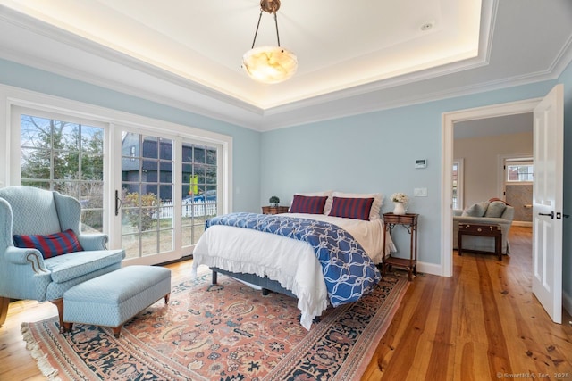 bedroom with access to exterior, light wood finished floors, a raised ceiling, and baseboards