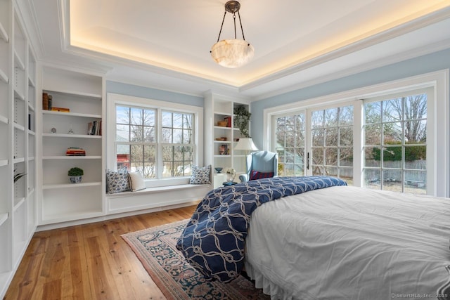 bedroom featuring a raised ceiling, wood-type flooring, and ornamental molding