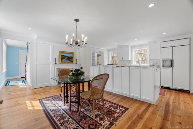 dining space featuring light wood finished floors, crown molding, baseboards, recessed lighting, and an inviting chandelier