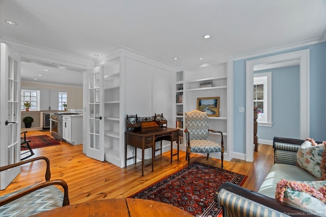 living room featuring ornamental molding, built in features, french doors, wine cooler, and light wood finished floors