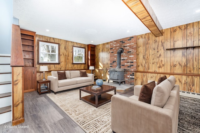 living room featuring hardwood / wood-style floors, a wood stove, a textured ceiling, and wooden walls