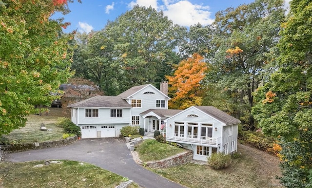 201 Shore Rd, Greenwich, CT 06830 - tri-level home with roof with shingles, a chimney, an attached garage, and driveway