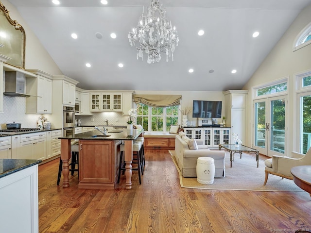 201 Shore Rd, Greenwich, CT 06830 - interior space featuring wall chimney range hood, high vaulted ceiling, a kitchen breakfast bar, and tasteful backsplash