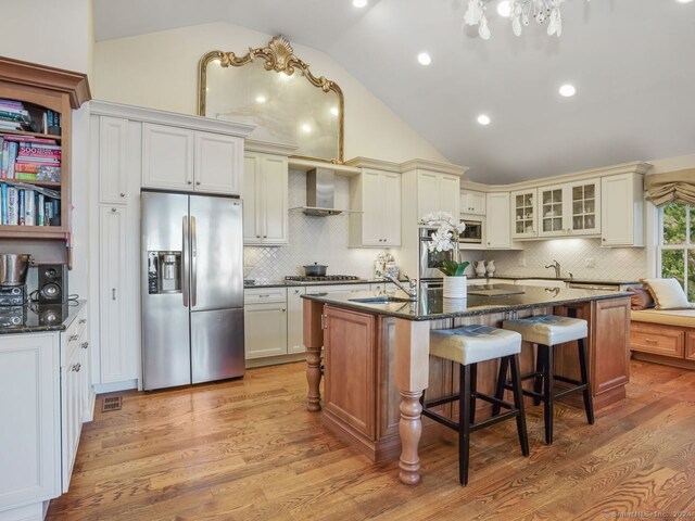 201 Shore Rd, Greenwich, CT 06830 - kitchen featuring stainless steel appliances, wall chimney range hood, vaulted ceiling, a sink, and light wood-style floors