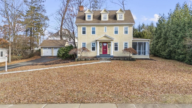 view of front of property featuring a sunroom, an outbuilding, and a garage