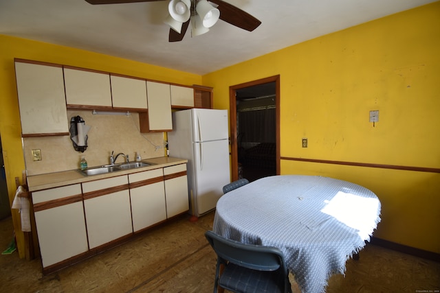 kitchen featuring ceiling fan, white refrigerator, sink, and white cabinets