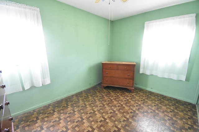 empty room with dark parquet flooring and ceiling fan