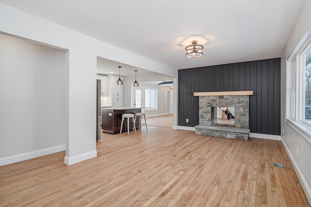 unfurnished living room featuring a stone fireplace and light hardwood / wood-style floors